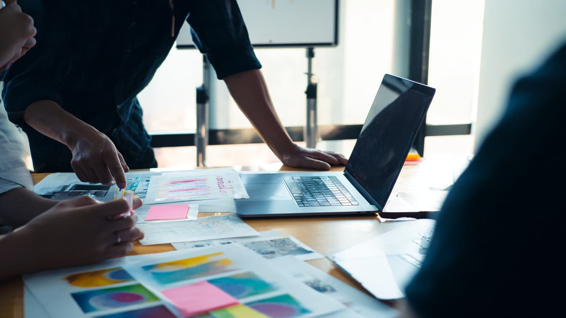 Kollaborative Arbeitssitzung mit Dokumenten und Laptop auf hellem Holztisch - Symbol für moderne Procurement-Architektur