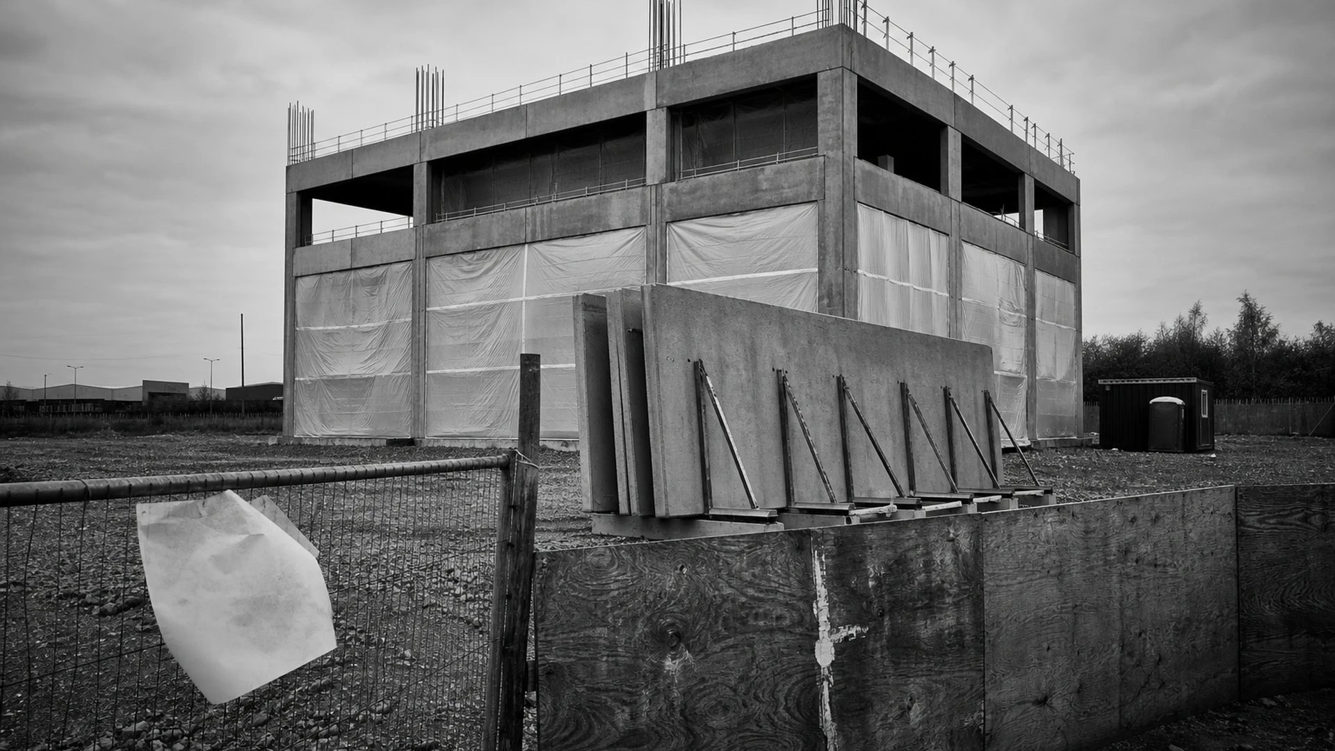 Halbfertiger Betonrohbau einer neuen Rechenzentrumshalle auf einem leeren Schotterplatz am Rand eines Industriegebiets