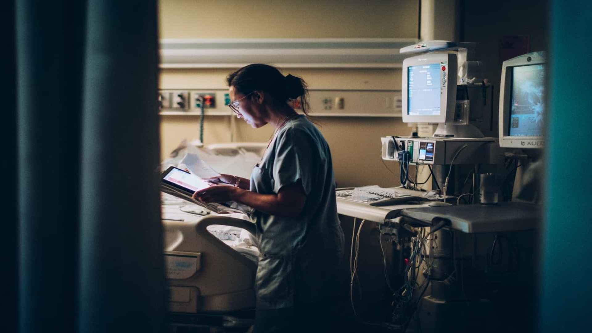 KI im Gesundheitswesen: Gesundheitsfachkraft analysiert Patientendaten mit Tablet in modernem Krankenhausumfeld