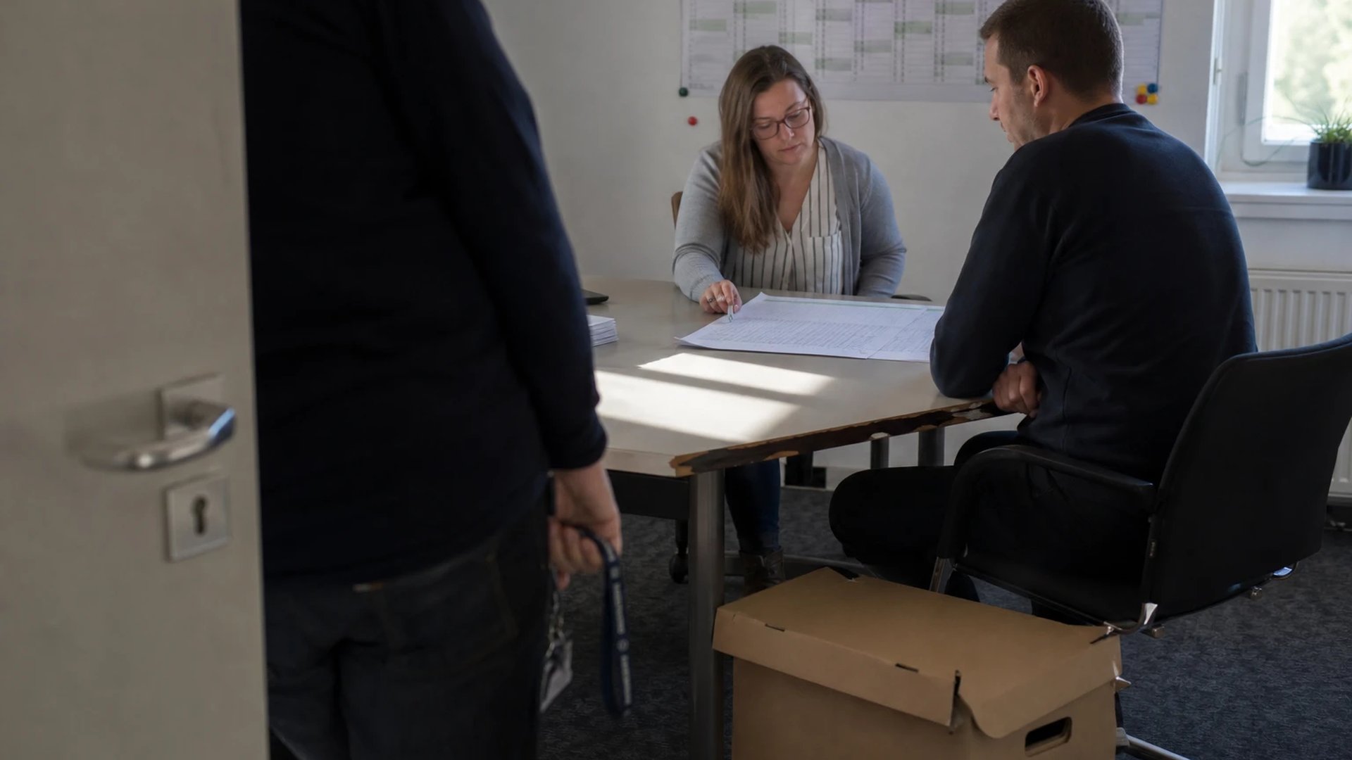Zwei Beschäftigte der Netzwirtschaft eines Stadtwerks sitzen an einem Bürotisch über einem ausgedruckten Kalkulationsbogen, im Hintergrund ein Jahresplaner