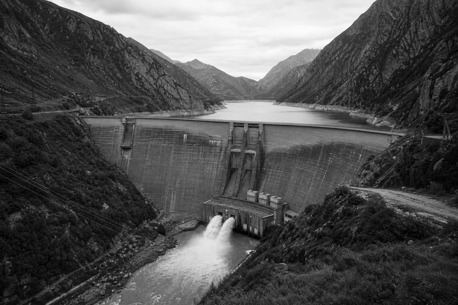 Large hydroelectric dam with a reservoir in a steep mountain valley, black and white photograph