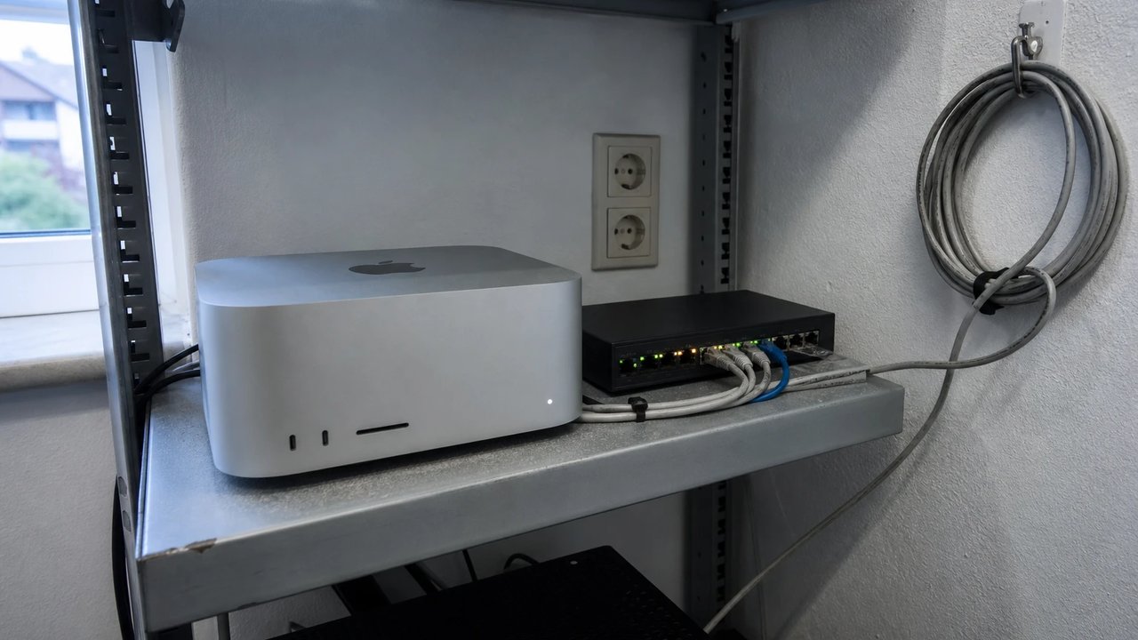Mac Studio on a metal shelf next to a network switch in a small office, a private local AI node