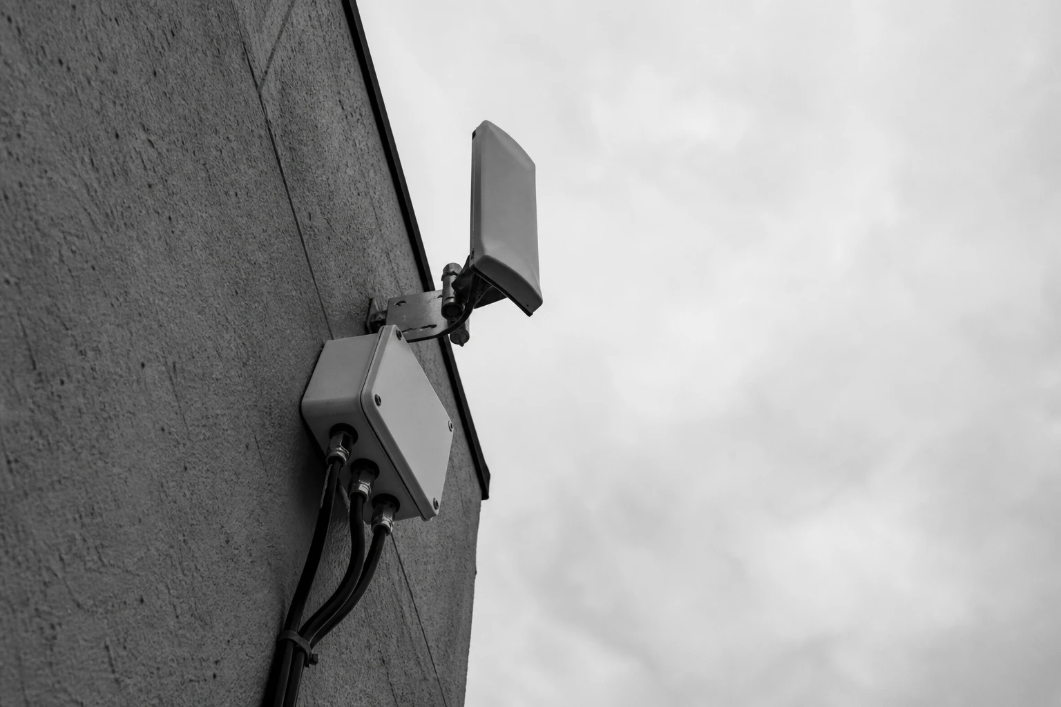 Sector antenna and a weatherproof communication box on a building wall, black and white