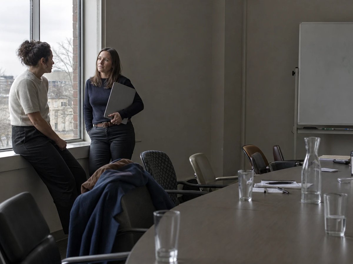 Two colleagues talking at the window of a meeting room in a municipal utility after a workshop