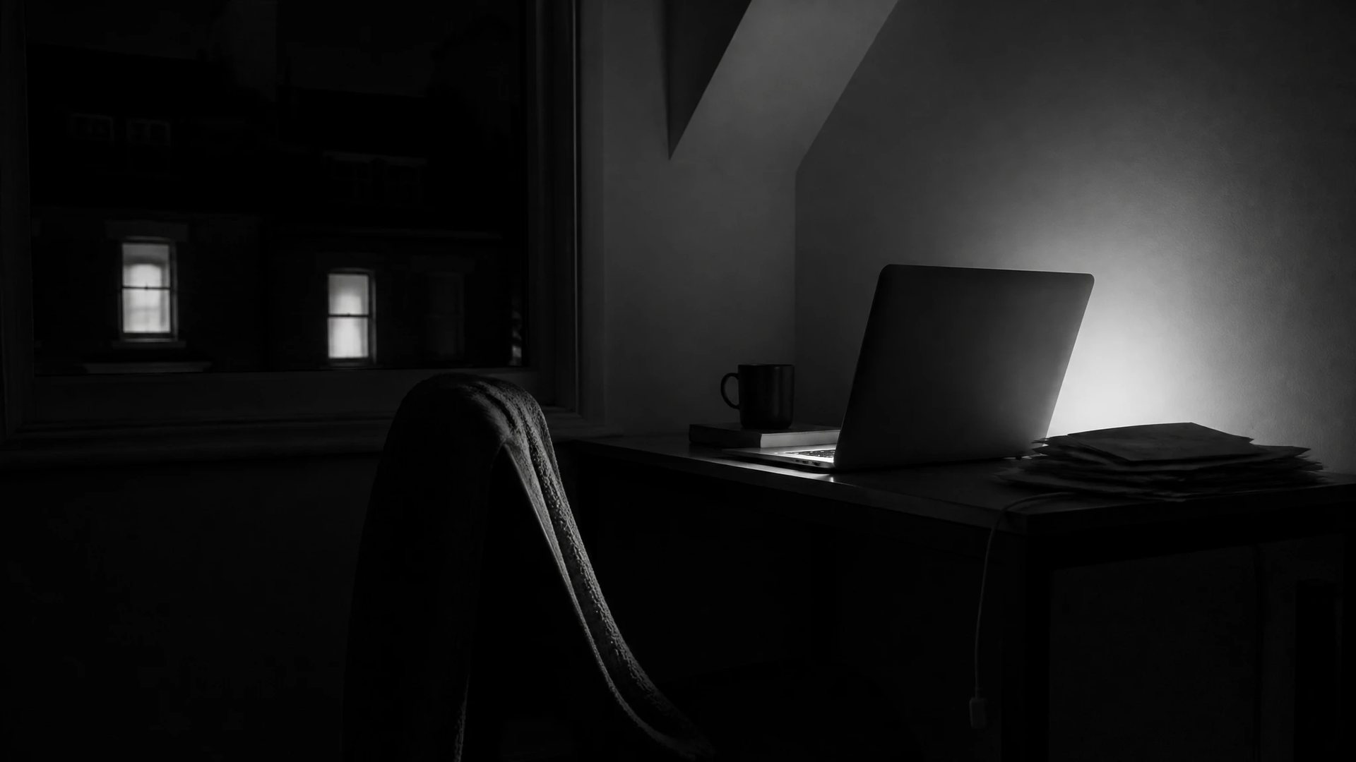 Home office corner after two in the morning, the laptop the only light source on the wall